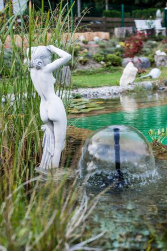 a statue of a woman standing in a pond at Gästehaus Waldrand Garni in Wiesing
