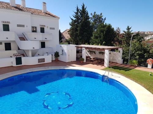 a villa with a swimming pool in front of a house at Cosy apartment close by Parque de la Paloma Benalmádena in Benalmádena