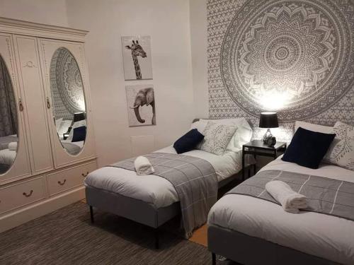 a bedroom with two beds and a mirror at Corner House, Sleeps 8 in 4 Bedrooms, near train station, Great Value! in Manchester