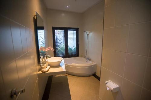 a bathroom with a tub and a sink and a toilet at Jirna House in Ubud