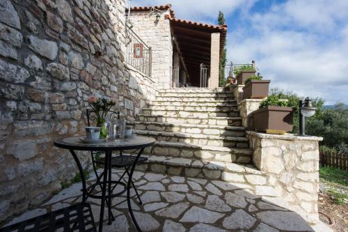 a small table in front of a stone building with stairs at Petra Thea Villa Karitaina in Karítaina