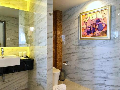 uma casa de banho com um lavatório e uma pintura na parede em The Green View Hotel em Ban Khlong Sanam Phli