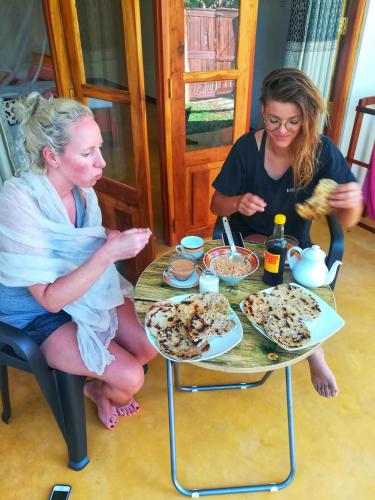 two women sitting at a table eating food at Relax Beach House in Tangalle