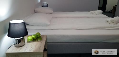 a hotel room with a bed and a night stand with a table with green apples at Willa Czarnieckiego in Warka