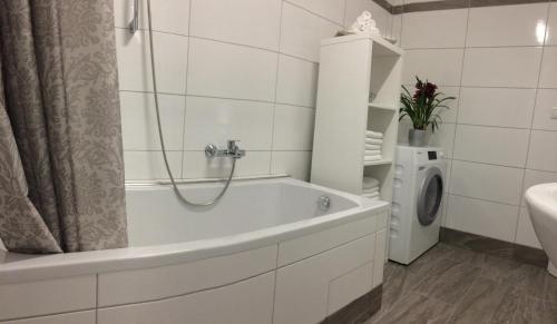 uma casa de banho com uma banheira e uma máquina de lavar roupa em Art Chic - your exklusive stay em Grödig