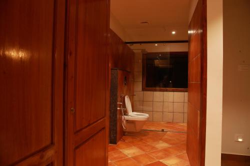 a small bathroom with a toilet and a door at Wild Saga in Thekkady
