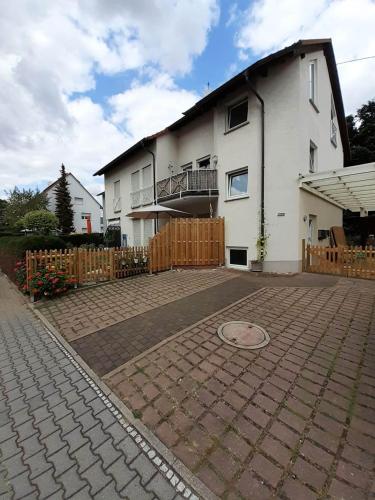 ein weißes Haus mit einem Zaun und einer steinernen Einfahrt in der Unterkunft Zimmer Frei 2 in Wiesbaden