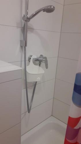 La salle de bains carrelée de blanc est pourvue d'une douche et d'un lavabo. dans l'établissement Zimmer Frei 2, à Wiesbaden