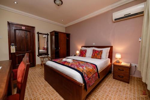 een hotelkamer met een bed, een tafel en een bureau bij Mahogany Lodge, Cantonments in Accra