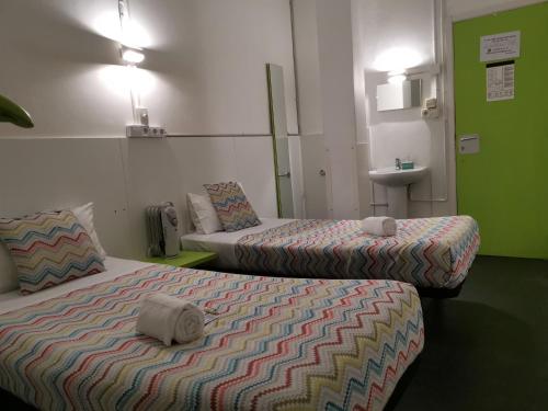 a room with two beds and a sink at Central and Basic Universitat for YOUNG HOSTEL in Barcelona