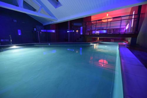 a large swimming pool in a house with purple lights at Kyriad Hotel Dijon Gare in Dijon