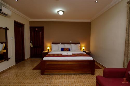 a bedroom with a large bed with two lamps at Mahogany Lodge, Cantonments in Accra
