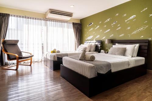 a bedroom with two beds and a chair at Ploen Place Residence in Pattaya Central