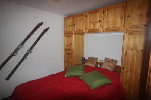 a bedroom with a bed with red sheets and green pillows at L'Atelier du Temps - La Petite maison de Pepa in La Salle