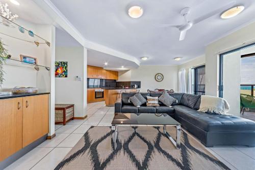 a living room with a black leather couch at Ambience of Airlie - Airlie Beach in Airlie Beach