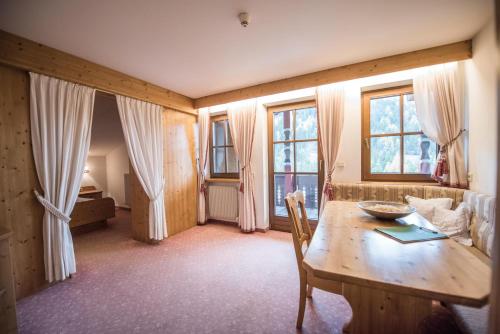 ein Wohnzimmer mit einem Holztisch und Fenstern in der Unterkunft Hotel Edelweiss in Prags