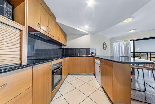 a kitchen with wooden cabinets and a counter top at Ambience of Airlie - Airlie Beach in Airlie Beach