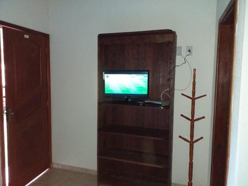 a room with a tv on a wooden entertainment center at Cháles Terra Nativa in Monte Verde