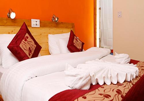 2 camas en una habitación con paredes de color naranja en Royal Heritage Resort, en Leh
