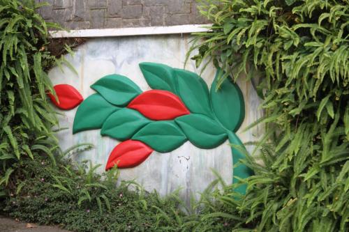 a wall with a painting of a flower on it at Chandys Windy Woods Munnar in Munnar