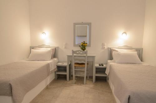 Zimmer mit 2 Betten und einem Tisch mit einem Stuhl in der Unterkunft Aspes Village in Aegiali