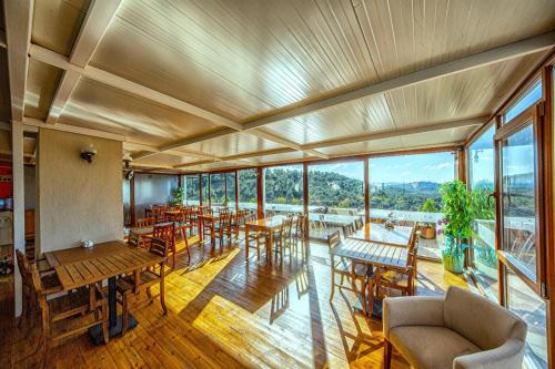 a restaurant with tables and chairs and windows at Kazdaglari Ida Natura Bungalov Hotel in Akcay