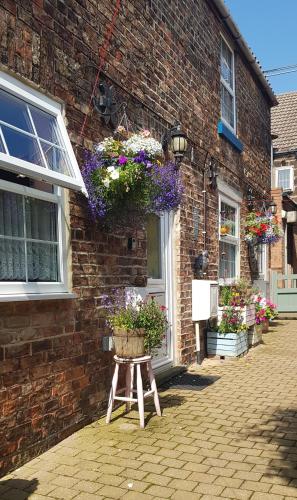 a building with flower baskets on the side of it at Saltburn Holidays Primrose Cottage in Guisborough
