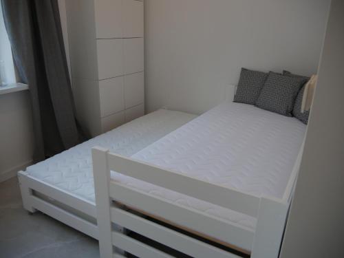 1 cama blanca pequeña en una habitación pequeña en Apartament pod Jaworzyną, en Krynica-Zdrój