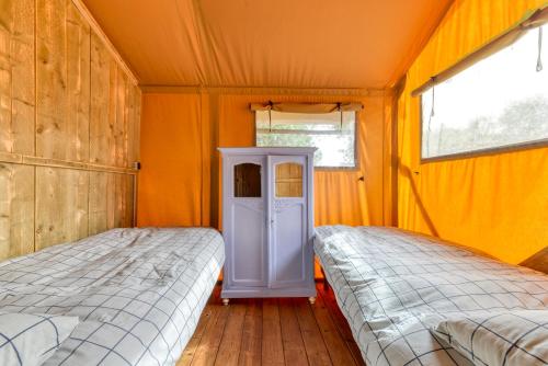 VélieuxにあるGlamping Tent Joyのオレンジ色の壁と窓が備わる客室で、ベッド2台が備わります。