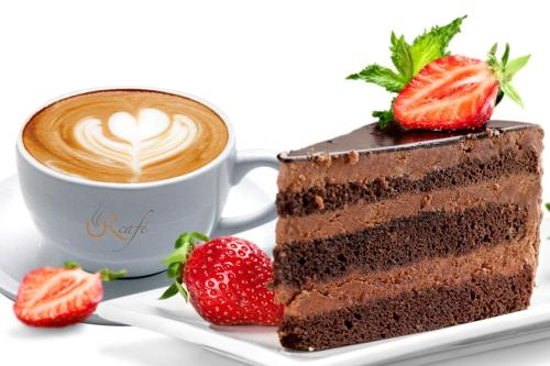 a piece of chocolate cake with a cup of coffee and strawberries at Ramada Hotel & Suites by Wyndham Ajman in Ajman 