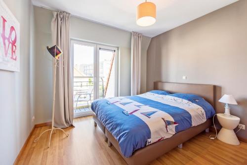 una camera con un letto e una grande finestra di Bright apartment with 2 terraces in De Panne a De Panne