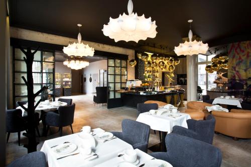 un restaurant avec des tables et des chaises blanches et des lustres dans l'établissement Empreinte Hotel & Spa, à Orléans