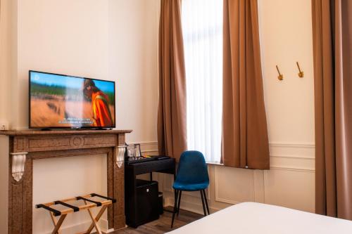 Habitación con TV, chimenea y silla azul. en La Lys Rooms & Suites, en Gante