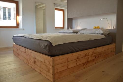 ein Bett auf einer hölzernen Plattform in einem Schlafzimmer in der Unterkunft Dimora Sannicolò - Talento in Rovereto