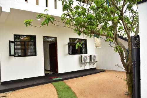Zimmer mit weißen Wänden und einem Baum in der Unterkunft Hikkaduwa Beach House in Hikkaduwa
