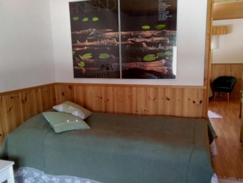 - un lit dans une chambre avec une photo sur le mur dans l'établissement Hotelli Möhkön Rajakartano - Ilomantsi, à Petkeljärvi