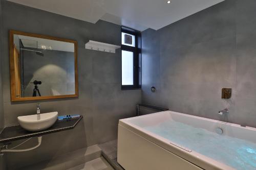 a bathroom with a tub and a sink and a mirror at Hotel Nova Boutique in Rajkot