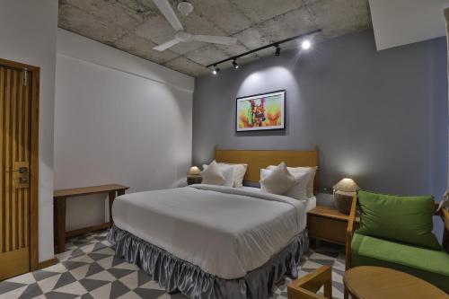 a bedroom with a bed and a green chair at Hotel Nova Boutique in Rajkot