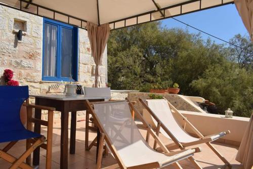 eine Terrasse mit Stühlen, einem Tisch und einem Fenster in der Unterkunft Marina Castellana Studios in Chalki
