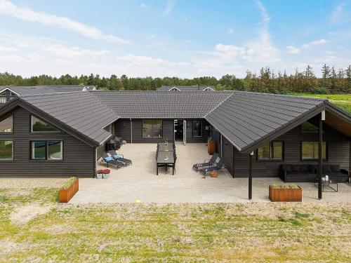 a house with a black roof and a patio at 20 person holiday home in Nørre Nebel in Nørre Nebel