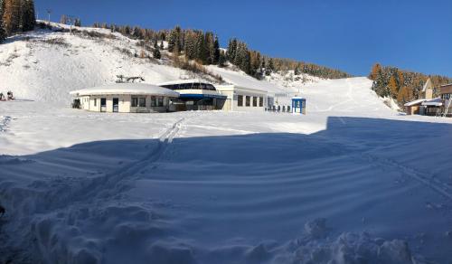 a snow covered building in front of a mountain at Piccolo Nido Falcade in Falcade