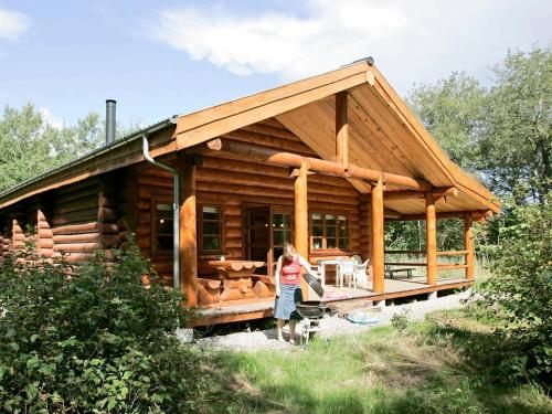 uma mulher em pé em frente a uma cabana de madeira em 10 person holiday home in Hadsund em Odde