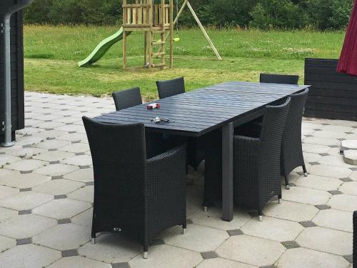 un tavolo nero e sedie su un patio con parco giochi di 10 person holiday home in Ansager ad Ansager