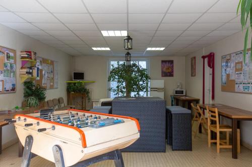 une salle avec un baby-foot, des tables et des chaises dans l'établissement Camping d'Autun, à Autun