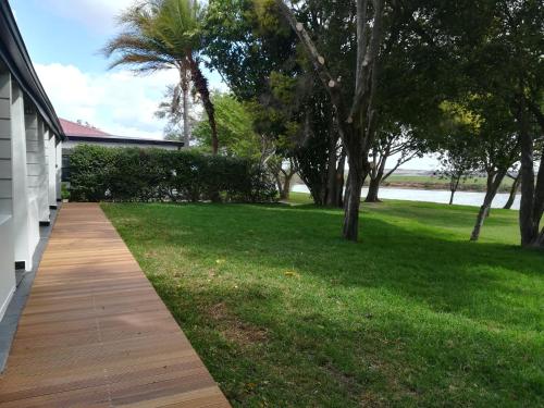 a wooden walkway next to a yard with trees at The Gamtoos Ferry Hotel in Jeffreys Bay