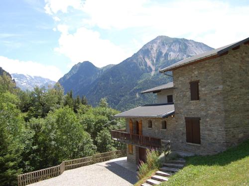 a stone house with mountains in the background at Magnificent chalet with sauna in Le Villard