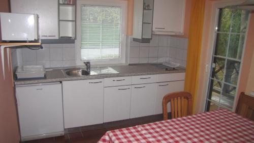a kitchen with white cabinets and a sink and a table at Terme Olimia - Apartment Village Lipa in Podčetrtek