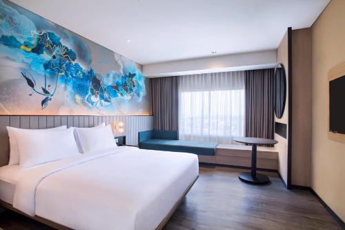 a bedroom with a large white bed and a couch at Mercure Bengkulu in Bengkulu