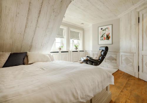 a bedroom with a large bed and a chair at SalzWasserHerz Senhoog Luxury Holiday Homes ***** in Morsum