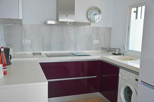 uma cozinha com um lavatório e um relógio na parede em Luna de Nerja em Nerja